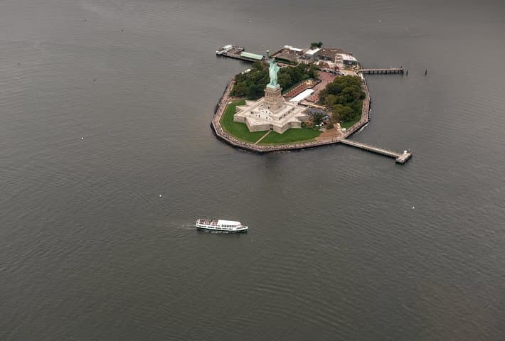 Lady Liberty, Ellis Island, and ferry boat as seen from a helicopter tour.